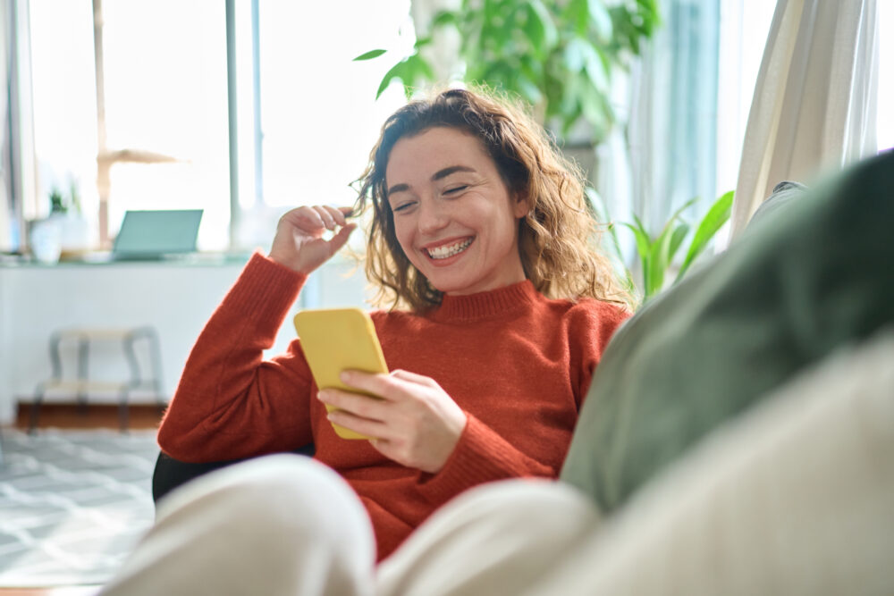 Junge lachende Frau mit Smartphone in der Hand