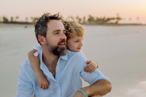 die Bayerische Versicherung Vater mit Kind am Strand blickt in die Ferne