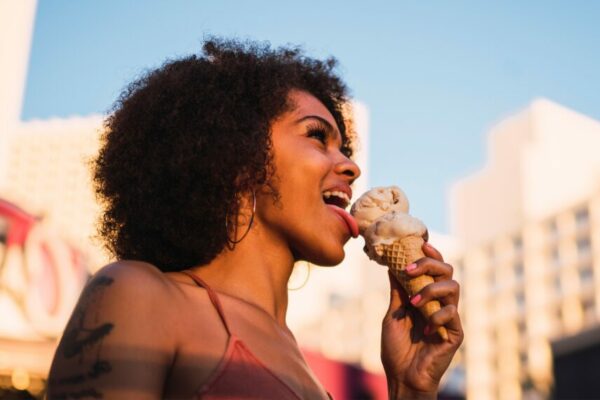 die Bayerische Versicherung Frau mit dunklen Locken leckt an Eis